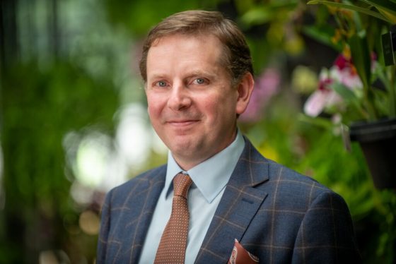 A person in a blue suit jacket and white shirt looking at the camera. 